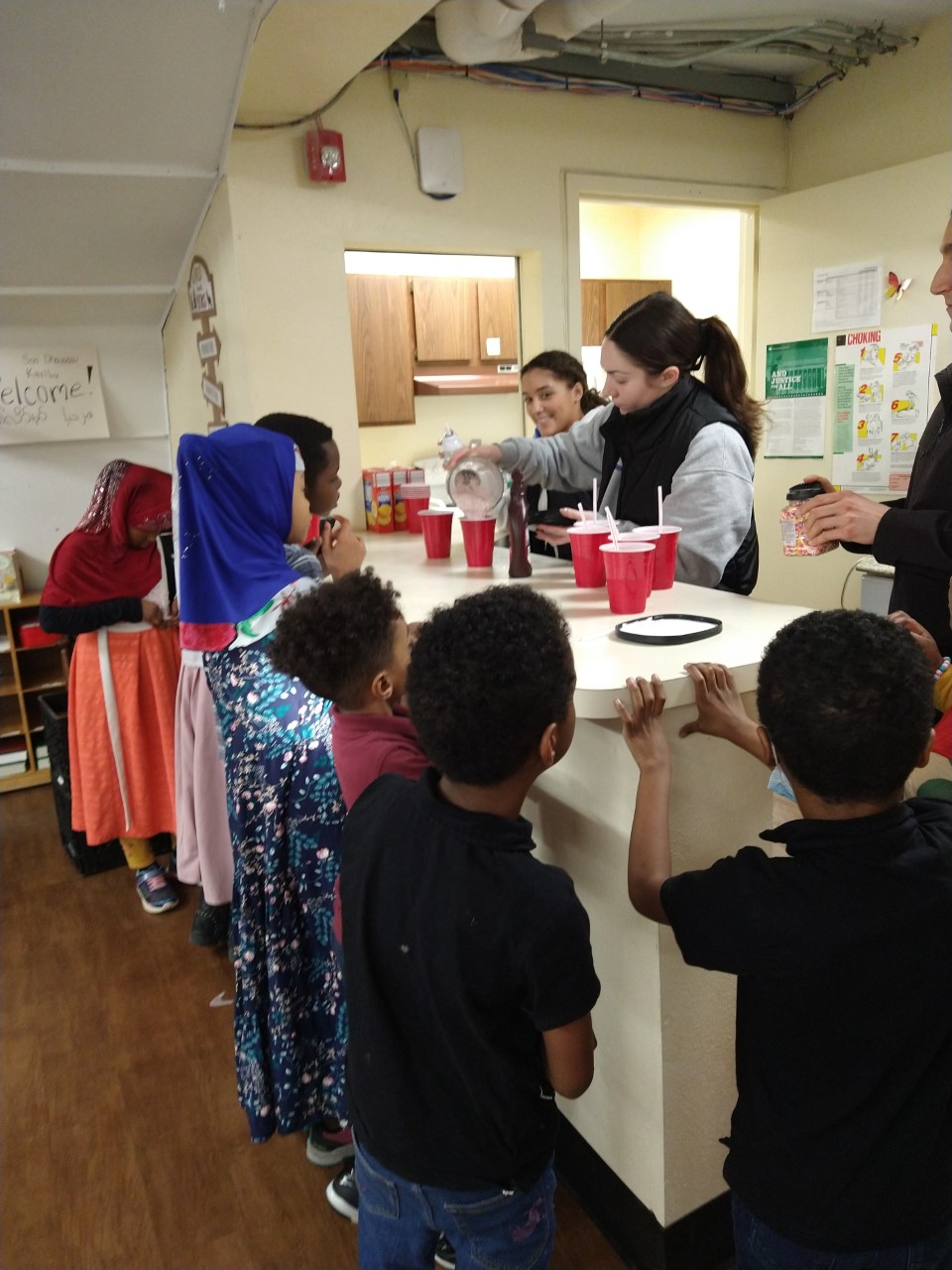 Seven elementary school students and one adult volunteer making home made milkshakes 